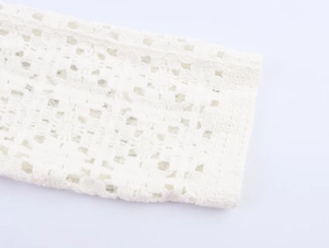 Macro detail of intricate white crochet knit pattern and delicate lace craftsmanship