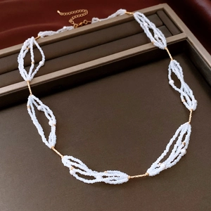 Detail of beaded glass pearl necklace with gold links and lobster clasp on brown display