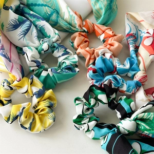 Detailed flat lay of colorful tropical floral scrunchies with long ribbons on white background