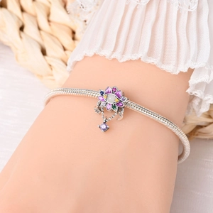 Detailed shot of 925 silver charm bracelet featuring purple floral enamel and gemstones
