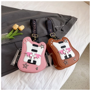Pink and brown guitar-shaped crossbody bags with star and wing details on a white bed
