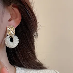 Detailed macro view of elegant pearl hoop earrings with gold textured base on model
