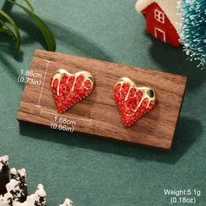 Vintage heart earrings with red zircon and gold trim on festive holiday background