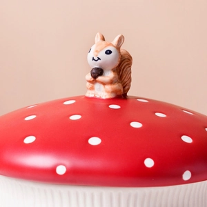 Detail of red mushroom ceramic lid featuring white polka dots and a tiny squirrel topper