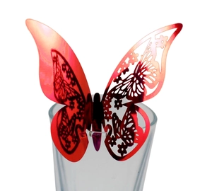 Macro detail of a laser-cut red metallic butterfly decoration on a glass rim
