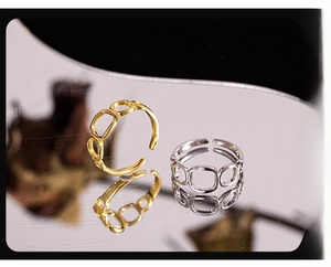 Close-up of geometric hollow square link rings in gold and silver with mirror reflection