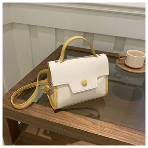 Macro detail of lychee textured leather and flap button on cream and yellow crossbody bag