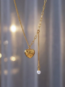 Détail du pendentif cœur texturé en or 18 carats avec chaîne et gland en perle