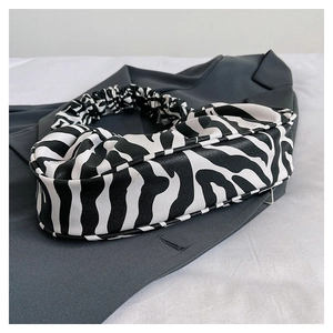 Detail of zebra print underarm bag with pleated cloud handle on dark grey fabric