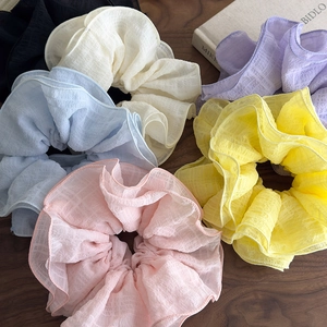 Oversized layered ruffle scrunchies in multiple pastel colors on a rustic wooden desk