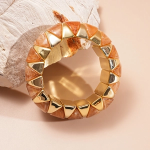 Close-up of geometric stretch bracelet with gold metal and orange marbled resin triangles