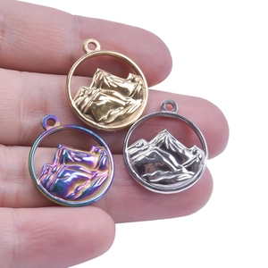 Detailed close-up of mountain relief pendants in gold, silver, and rainbow steel finishes