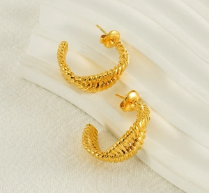 Close-up of golden stainless steel hoop earrings with an irregular twisted design