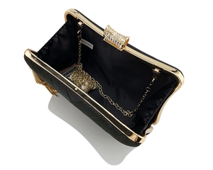 Top view of open black evening clutch with gold metal frame and interior chain strap