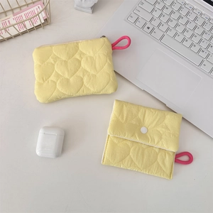 Detailed shot of yellow heart quilted pouches with pink cord charms on a desk