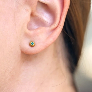Close-up of sterling silver gold-plated earring featuring a round turquoise stone