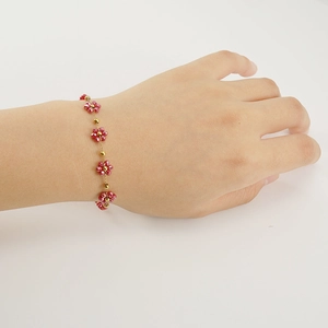 Bohemian 18K gold stainless steel bracelet with red crystal flowers on a model wrist