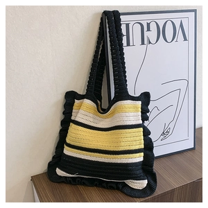 Detail view of a striped knit tote bag with ruffled edges on a wooden surface