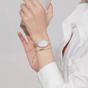 Detail shot of an oval gold quartz watch and minimalist bracelet set on a wrist
