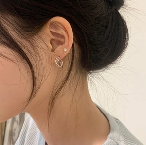 Close-up of twisted rope silver hoop earrings with small diamond stud on female model