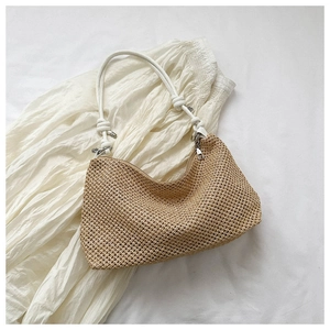 Macro detail of hand-woven straw tote with white rope shoulder strap and metal ring