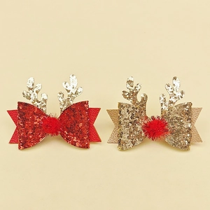 Detail of red and gold glitter reindeer antler hair clips with festive pom-poms