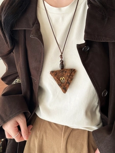 Close-up of heart-shaped gold jeans tag on a leopard print plush triangle pendant