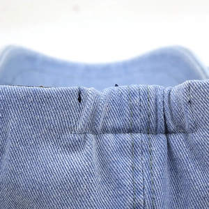 Close-up of light blue denim octagonal cap fabric showing twill weave and stitching