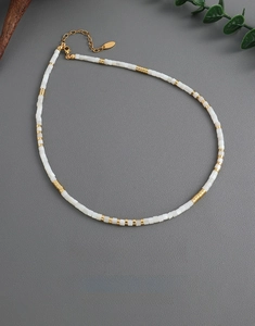 Detail of white shell beads necklace with gold-plated brass beads and lobster clasp