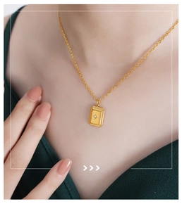 Detail of a vintage 18k gold square necklace with sparkling starburst zircon pendant