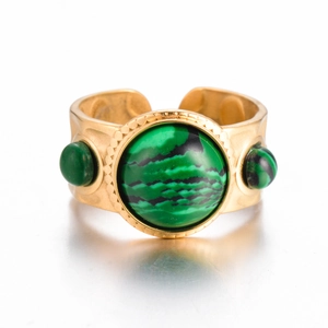 Macro detail of vintage gold titanium steel ring with green malachite stone and textured finish