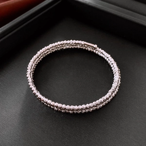 Macro shot of silver multi-layer twisted bracelet with diamond-cut texture on black background