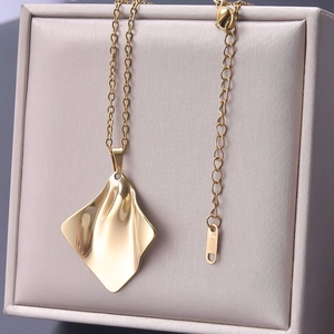 Close-up of golden stainless steel necklace with wave-textured square pendant on jewelry box