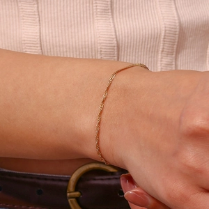 Elegante bracciale a catena a onde in acciaio placcato oro 18K indossato da una donna