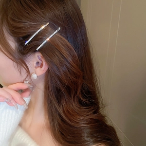 Close-up of sparkling rhinestone hairpins and pearl earrings on a model side profile