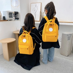 Adult and child wearing yellow anti-theft backpacks in different sizes, back view