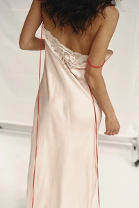 Detailed back view of pink satin slip dress with eyelash lace trim and red strap detail