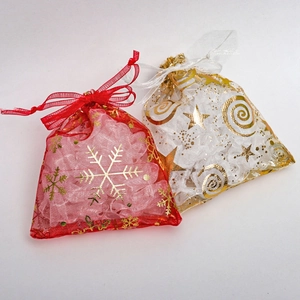 Detail of red snowflake and white star-moon gold foil patterns on organza gift bags