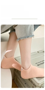 Close-up of light orange cotton ankle socks with cute white rabbit embroidery on the heel