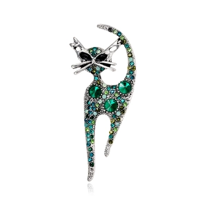 Vintage cat brooch featuring green crystal rhinestones on a silver metal base
