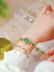 Detail of a gold quartz watch with green jade-like stones and a matching heart bracelet