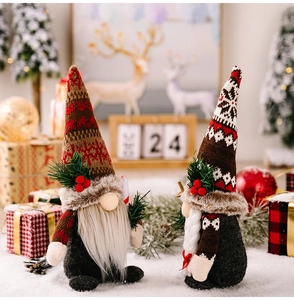 Close-up of plush Christmas gnomes with knitted hats, pine branches and festive berries