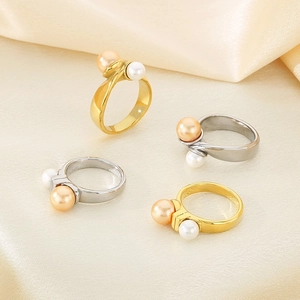 Close-up of pearl rings in gold and silver finish on elegant champagne silk fabric