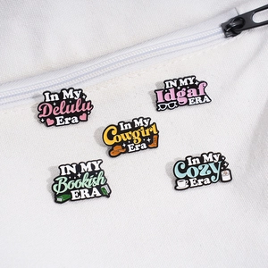 Set of five colorful enamel pins with English phrases on a white canvas bag