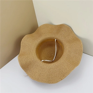 Detail showing wavy brim texture and white elastic chin strap of the woven straw hat