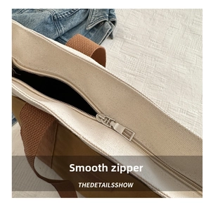 Detailed close-up of smooth metal zipper closure on contrast canvas tote bag