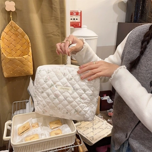 Détail de la trousse de toilette matelassée blanche avec motifs de lapins et fleurs