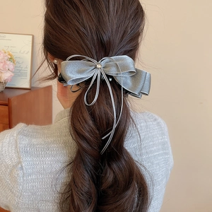 Detail of elegant silver satin bow hair clip with rhinestone on model's hairstyle