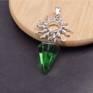 Detalle de un colgante de sol plateado vintage con cristal hexagonal verde