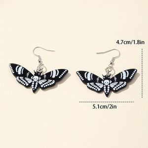 Detail view of black acrylic moth earrings with skull patterns and size dimensions